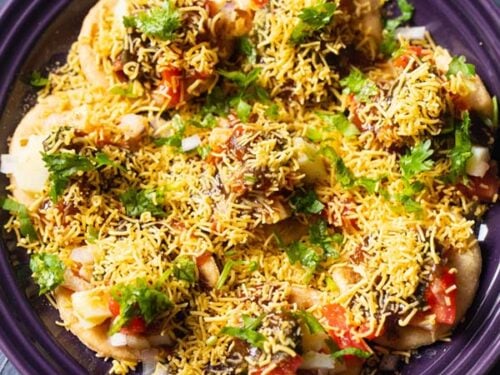 overhead shot of sev puri on a dark purple plate on a a dark blue table