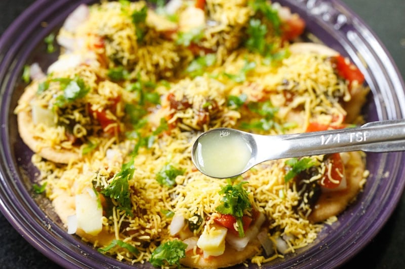 lemon juice in a measuring spoon on top of the prepared sev puri