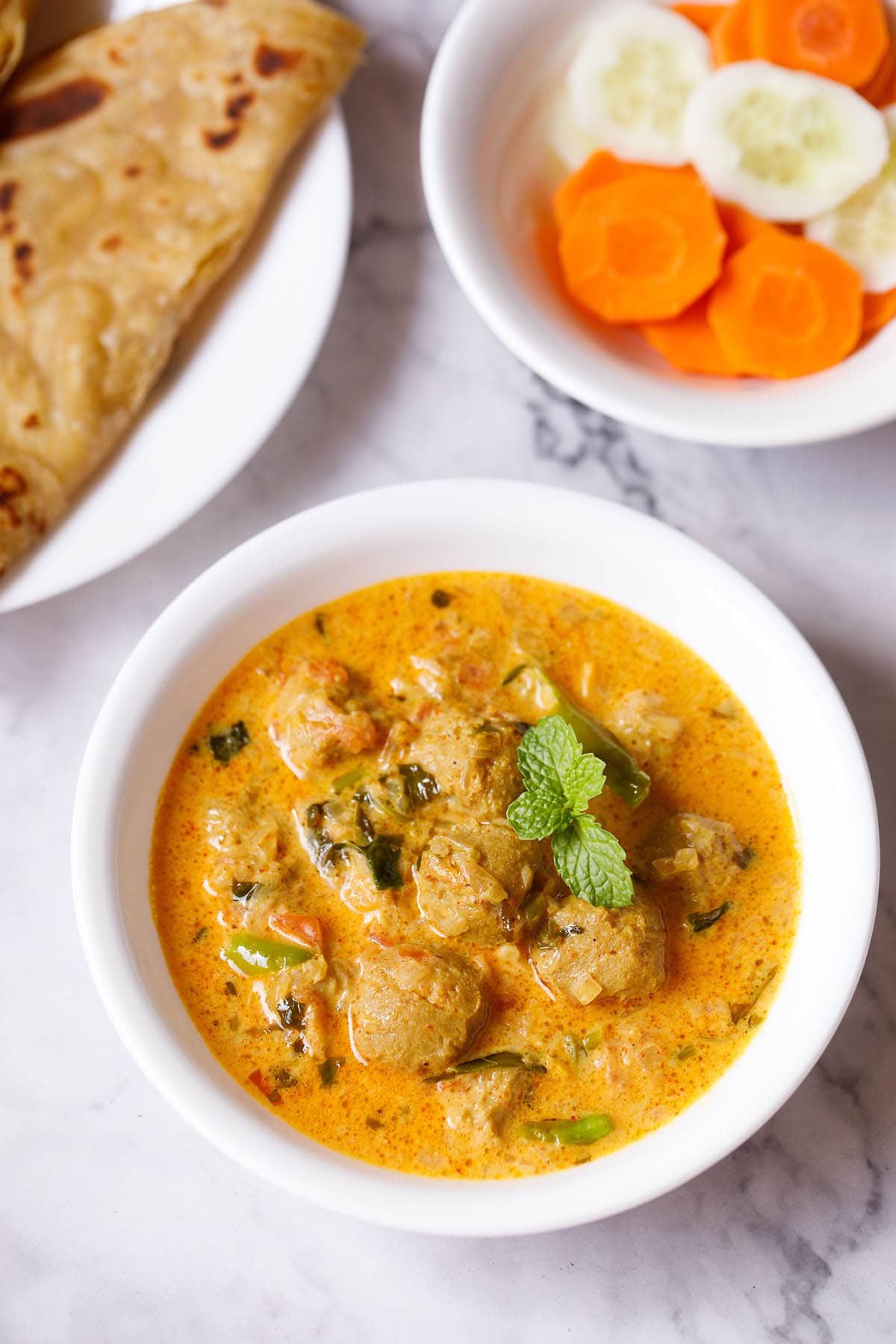 overhead shot of delicious soya chunks curry recipe in a white bowl garnished with mint