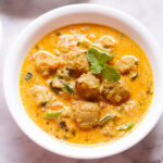 overhead shot of soya chunks curry in a white bowl garnished with mint leaves.