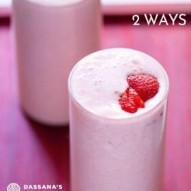 strawberry milkshake topped with strawberry slices in two glasses on a reddish pink tray with text layovers