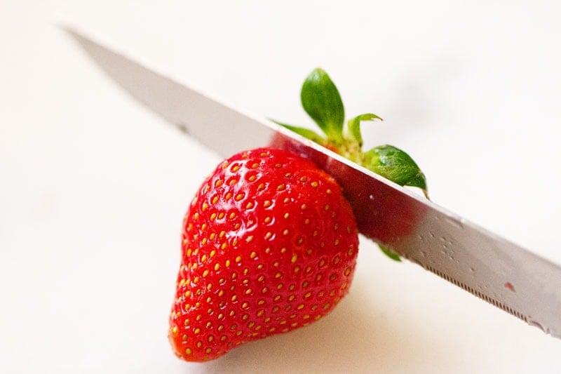 cutting strawberry on a white chopping board