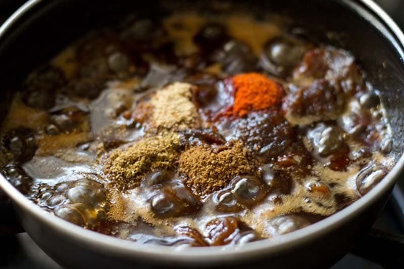 ground spices added to simmering dates and tamarind liquid in pan