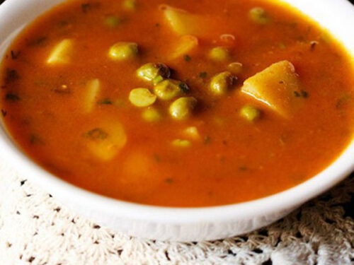 aloo matar curry served in a white bowl.