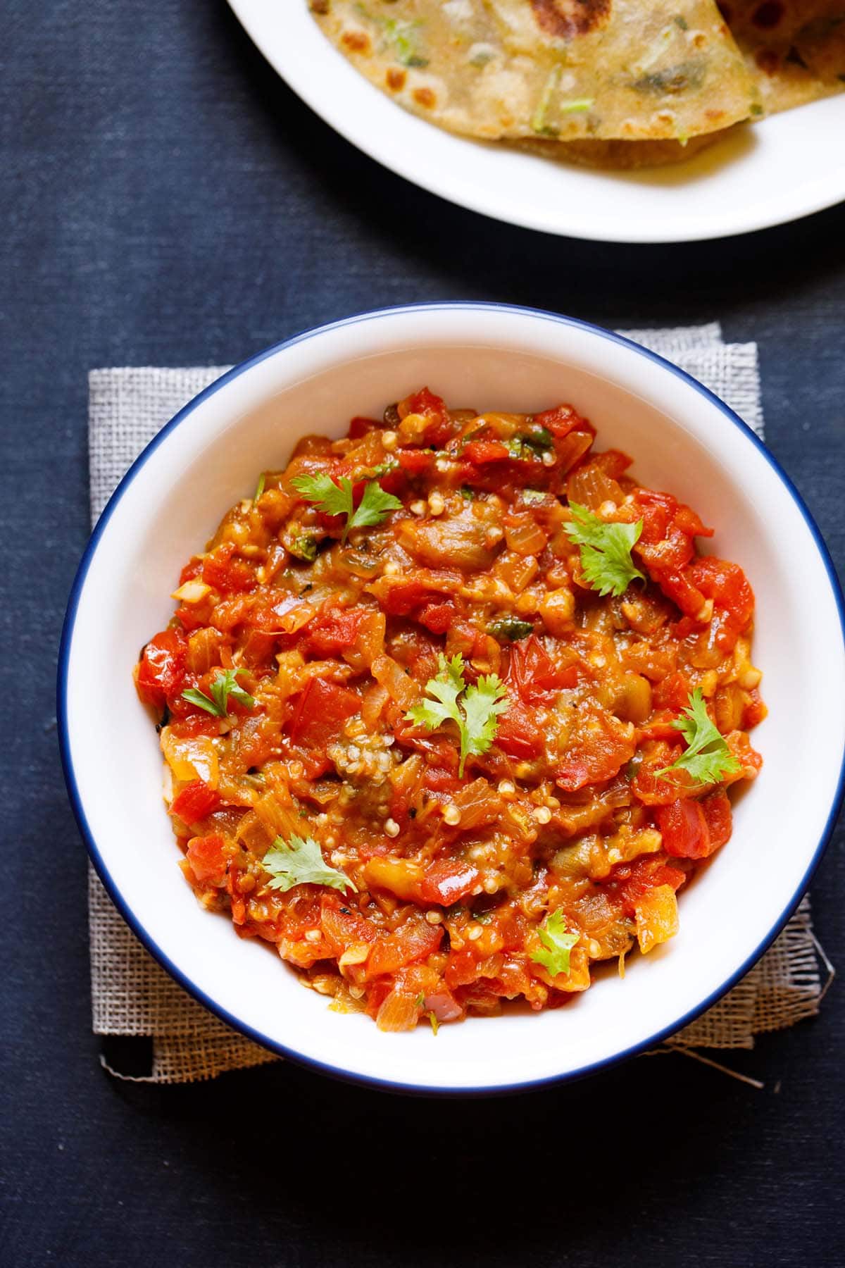 baingan bharta garnished with cilantro in a blue rimmed white bowl