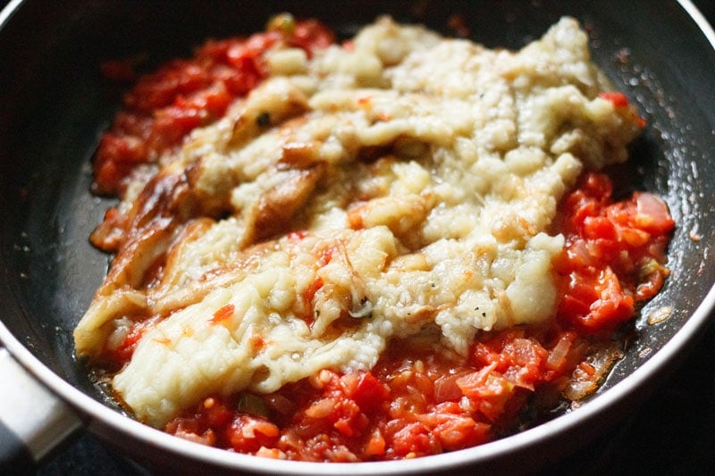 chopped cooked eggplant on the tomatoes in the pan