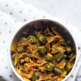 bhindi do pyaza in a white bowl on a golden polka dotted white napkin