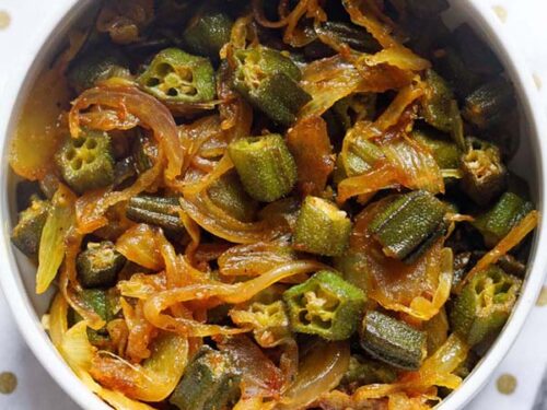 bhindi do pyaza in a white bowl on a golden polka dotted white napkin