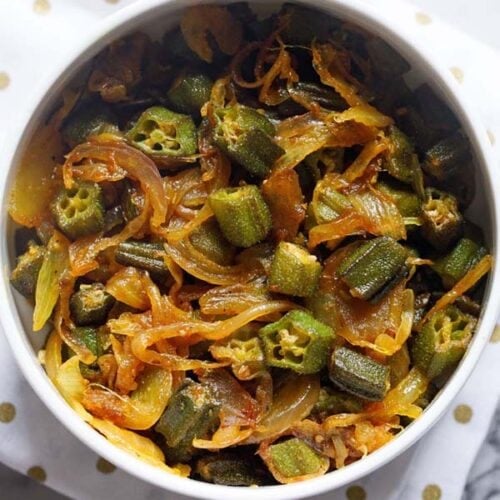 bhindi do pyaza in a white bowl on a golden polka dotted white napkin