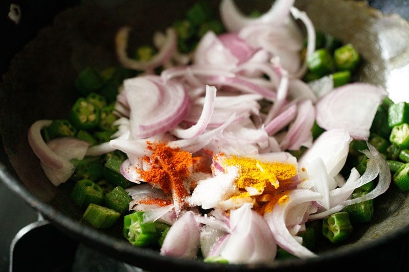 ground spices and salt on sliced onions in pan