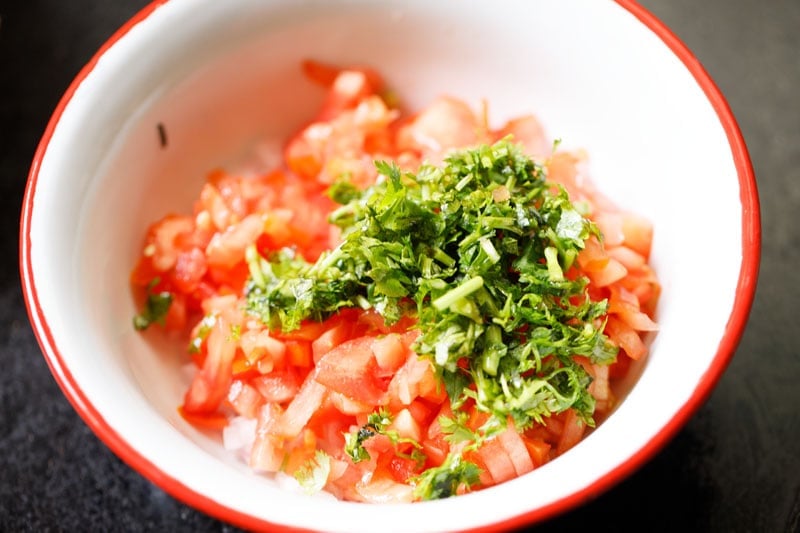 chopped tomatoes and cilantro added to onions and peppers