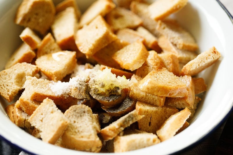 bread pieces with olive oil, salt and pepper in a mixing bowl