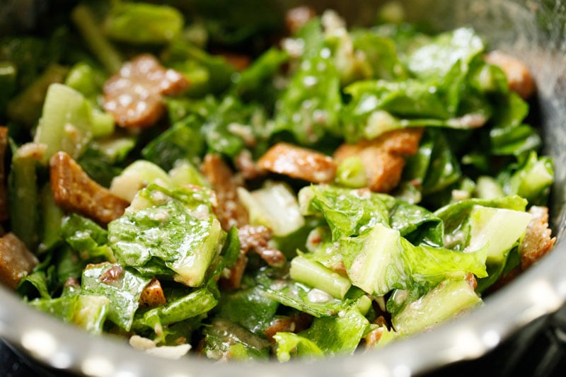 tossed vegetarian caesar salad in a silver mixing bowl