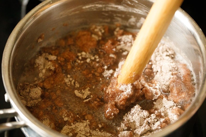wooden spoon stirring dry flour into ragi slurry