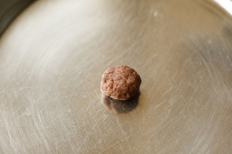 fingernail sized pinch of ragi mudde dough on a silver tray