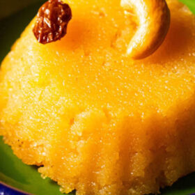 closeup shot of rava kesari served in dark green plate.