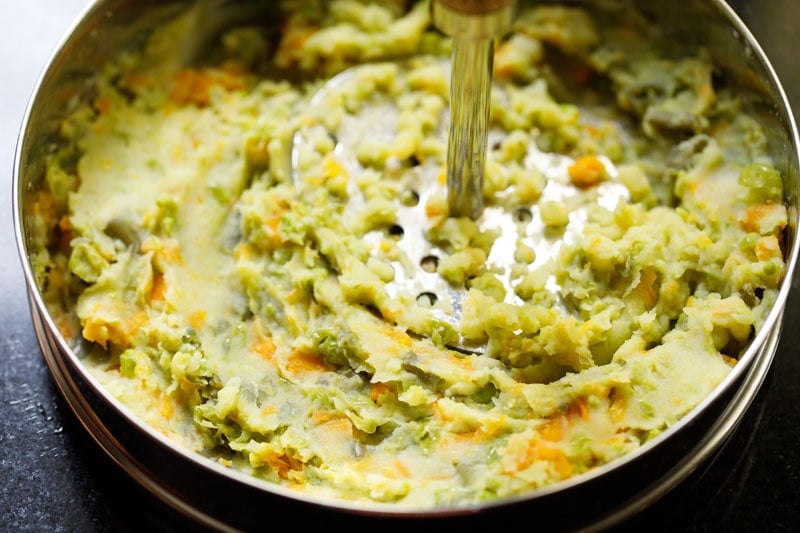 mashing veggies with a potato masher