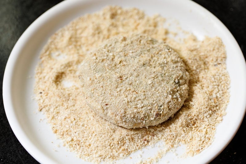 crumb coated cutlet on the breadcrumbs in white plate