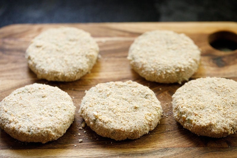 crumb coated cutlets on wooden board