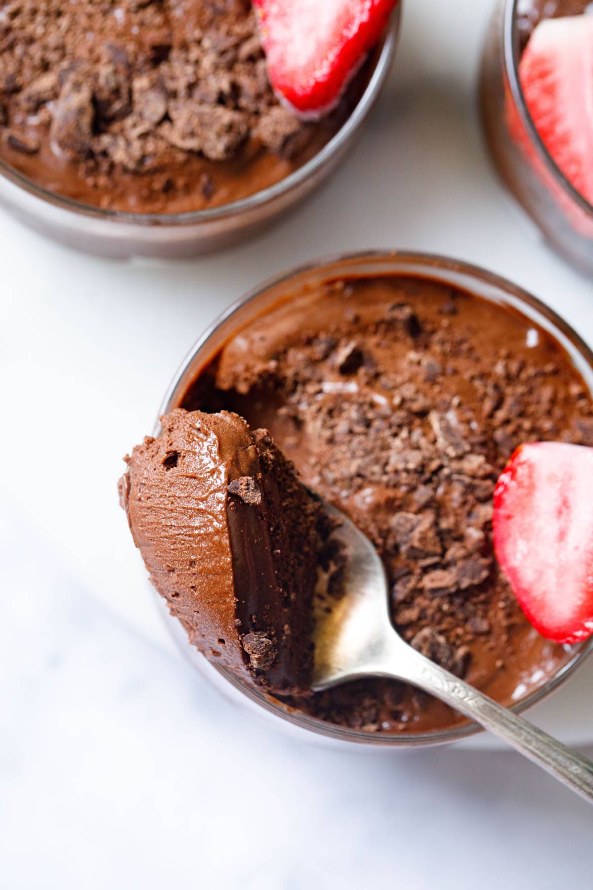 chocolate mousse scooped in a silver spoon showing its light fluffy texture placed on side of bowl filled with the mousse