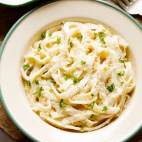 fettuccine alfredo sprinkled with grated parmesan and chopped parsley filled in a deep dish plate