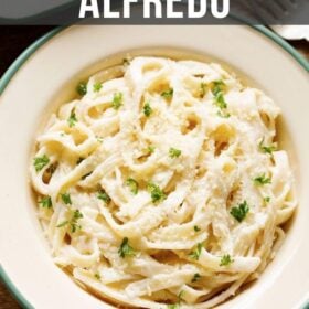 overhead shot of fettuccine alfredo sprinkled with grated parmesan and chopped parsley filled in a deep dish plate with text layovers