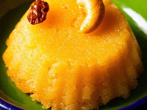 closeup shot of rava kesari served in dark green plate.