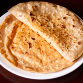 folded paneer paratha on top of a paneer paratha on a white plate