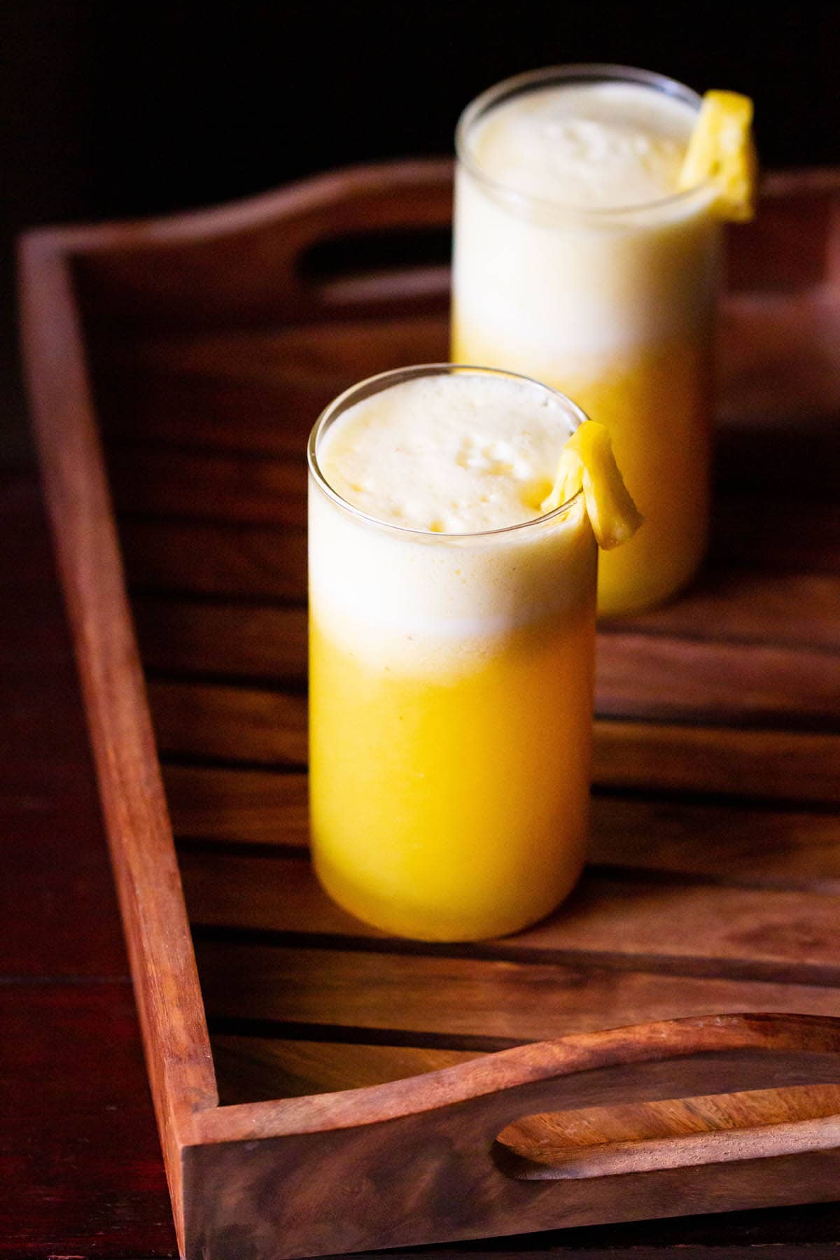 fresh pineapple juice served in two glasses and garnished with fresh pineapple pieces
