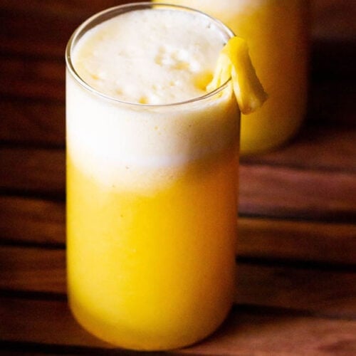 fresh pineapple juice served in two glasses and garnished with fresh pineapple pieces