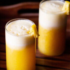 fresh pineapple juice served in two glasses and garnished with fresh pineapple pieces