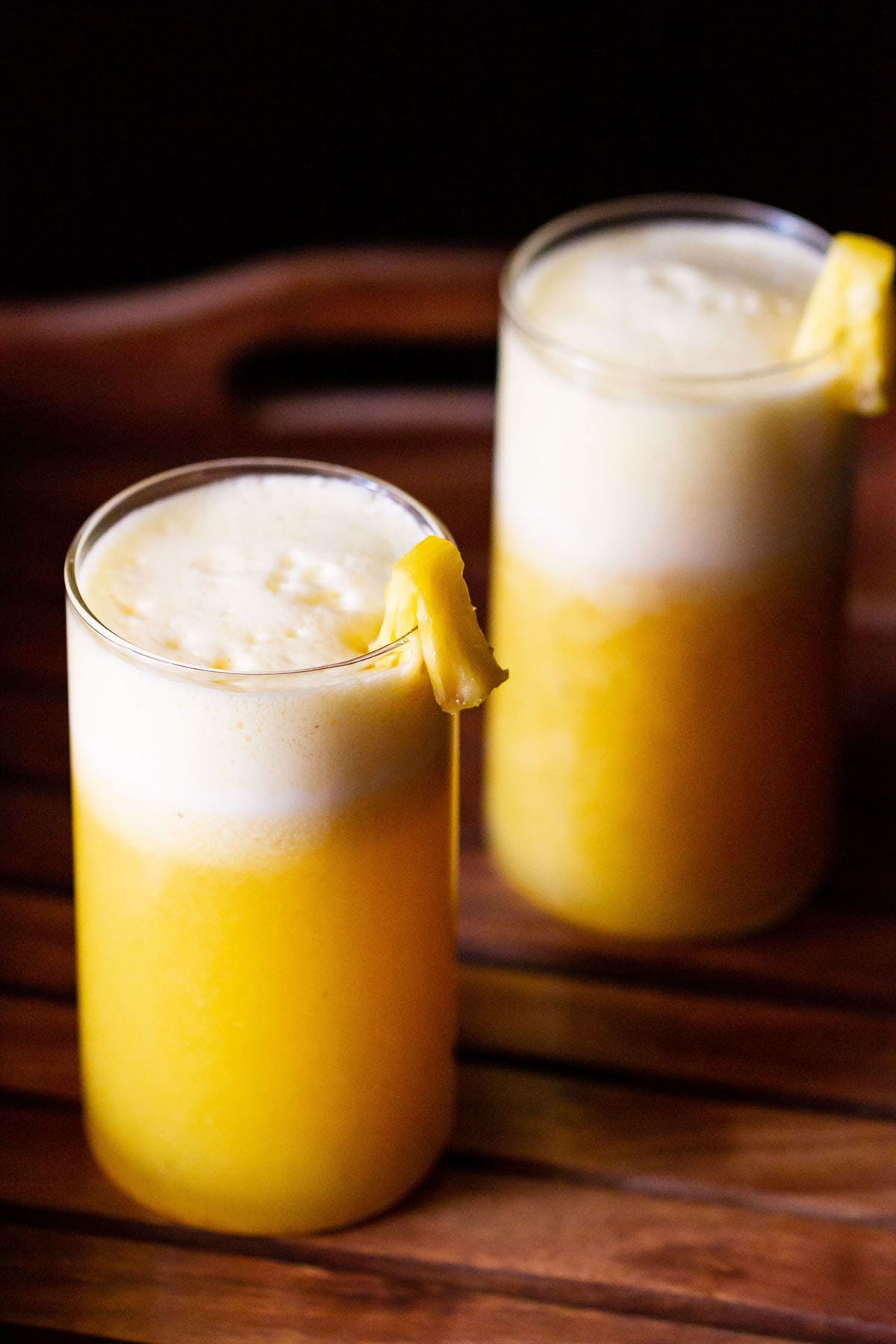 fresh pineapple juice served in two glasses and garnished with fresh pineapple pieces