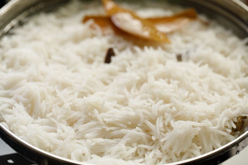 rice in a mesh strainer with spices visible on the top