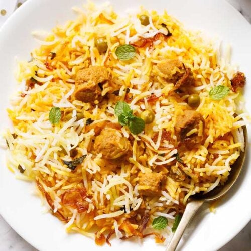 soya biryani in a white plate with a brass spoon on the plate