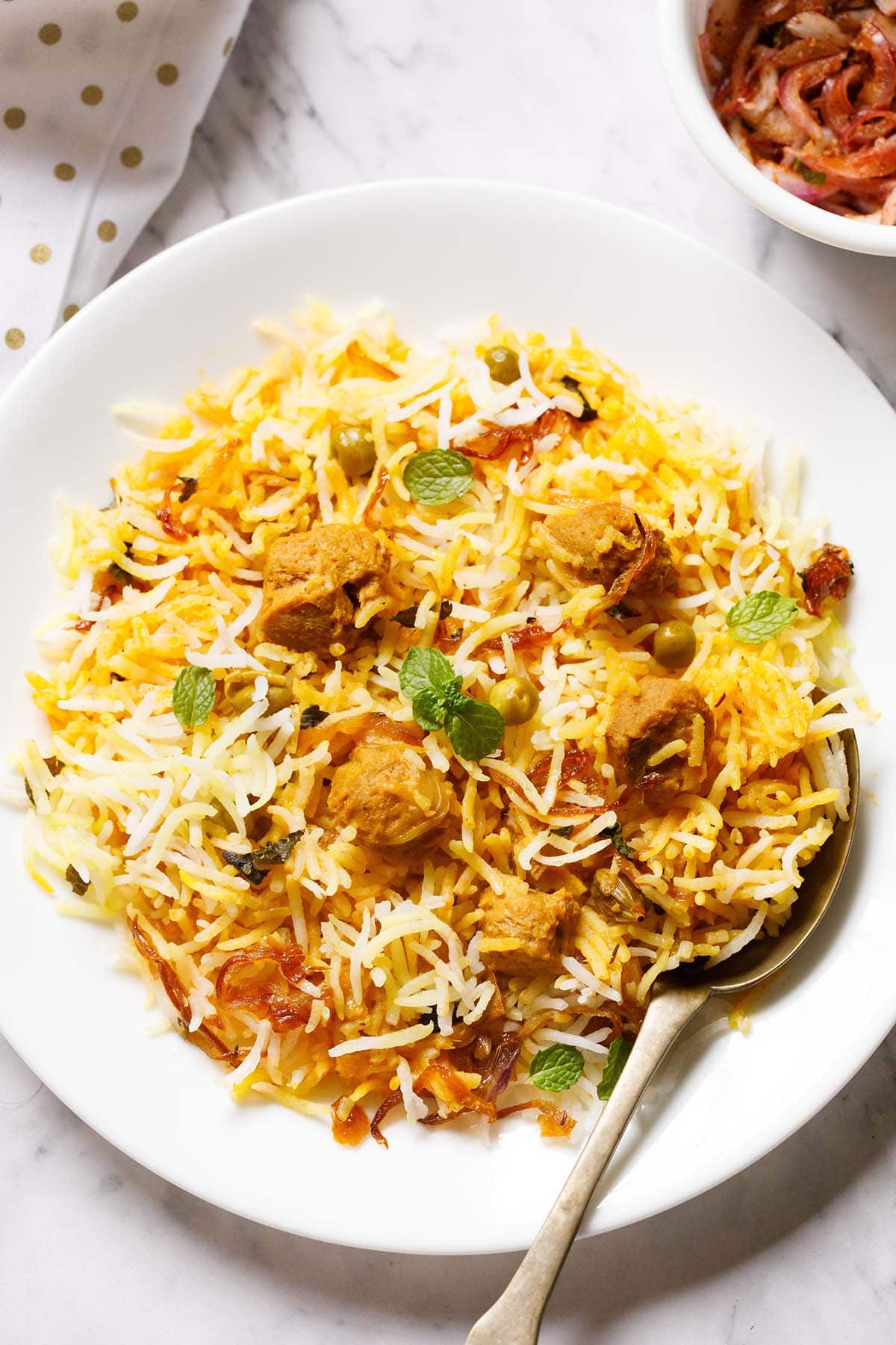 soya biryani in a white plate with a brass spoon on the plate