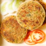 closeup shot of veg cutlet cutlet placed on a tray with a few slices of tomatoes, cucumber