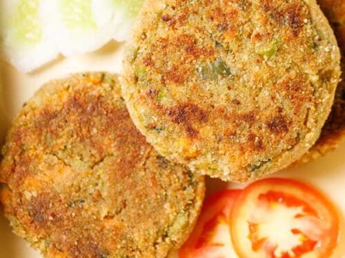 closeup shot of veg cutlet cutlet placed on a tray with a few slices of tomatoes, cucumber