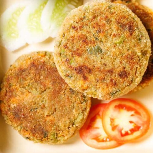 closeup shot of veg cutlet cutlet placed on a tray with a few slices of tomatoes, cucumber