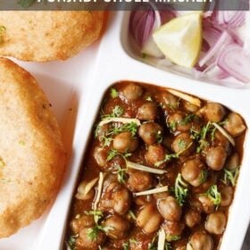 overhead shot of white plate with sections filled with chana masala, sliced onions, fresh lime wedges and bhatura on a marble table-top with text layovers.