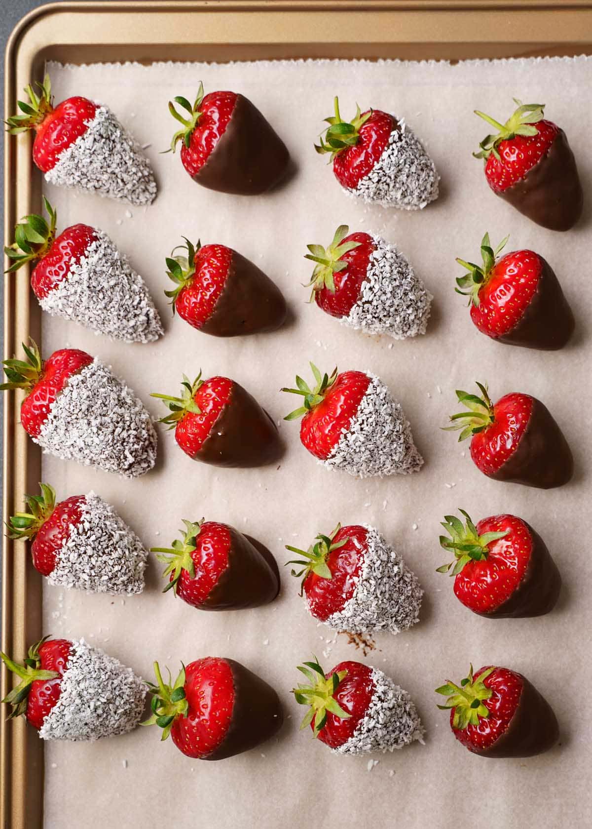 chocolate covered strawberries on a golden tray lined with parchment paper
