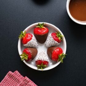 chocolate covered strawberries in a white bowl on black board