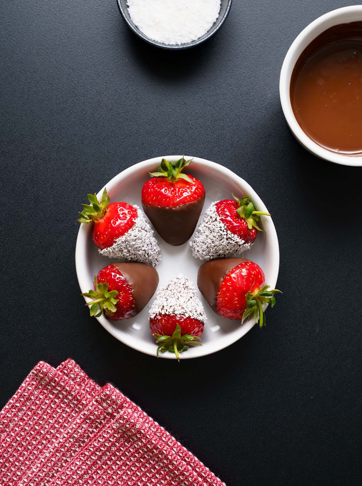 chocolate covered strawberries in a white bowl on black board