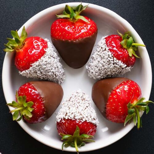 chocolate covered strawberries in a white bowl on black board