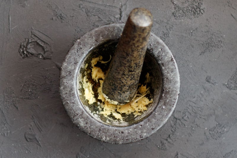 crushing ginger garlic in a mortar pestle