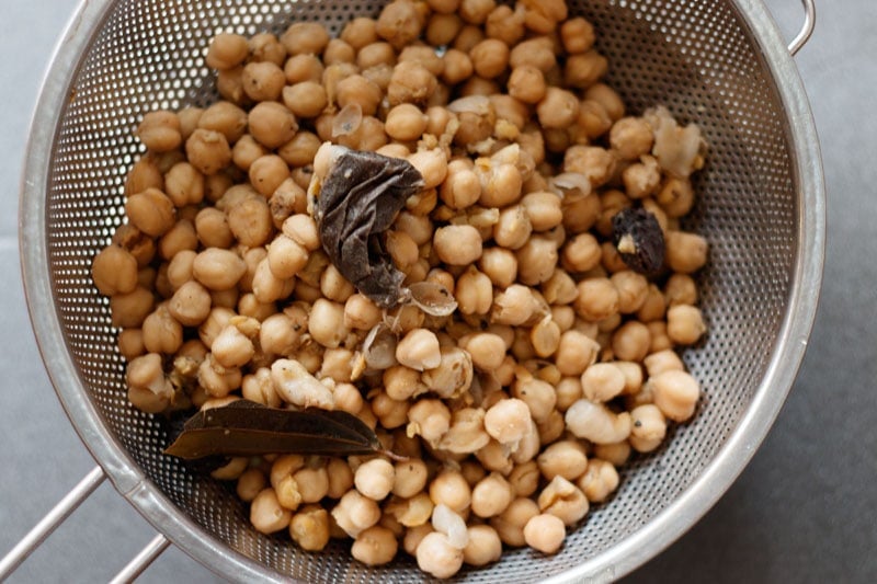 draining water from cooked chickpeas in a colander