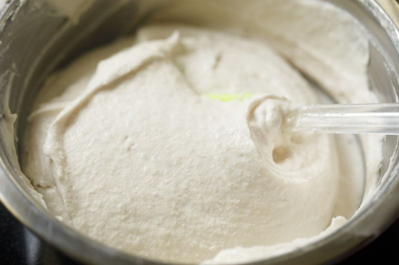 vada batter being whisked with a spatula in a steel bowl