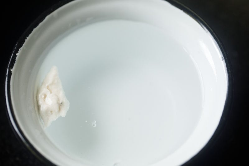 testing a small portion of batter in a white bowl filled with water