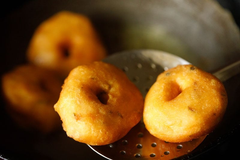 removing medu vada with a slotted spoon