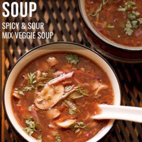 overhead shot of hot and sour soup with coriander garnish in a soup bowl with a white spoon inside on a dark brown bamboo tray with text layovers