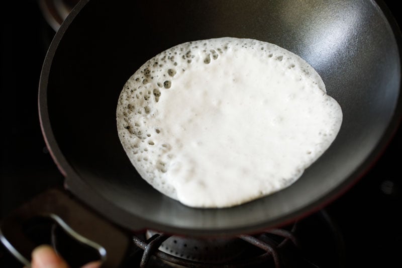 swirling dough around pan to create a round appam